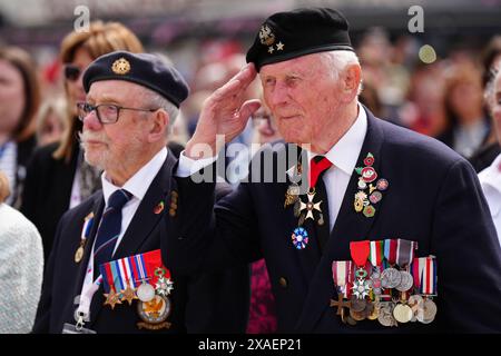 Il veterano Eugenius Nead saluta durante la sfilata dei veterani con lo Spirit of Normandy Trust, sul lungomare di Arromanches, in Normandia, Francia, per commemorare il 80° anniversario dello sbarco del D-Day. Data foto: Giovedì 6 giugno 2024. Foto Stock