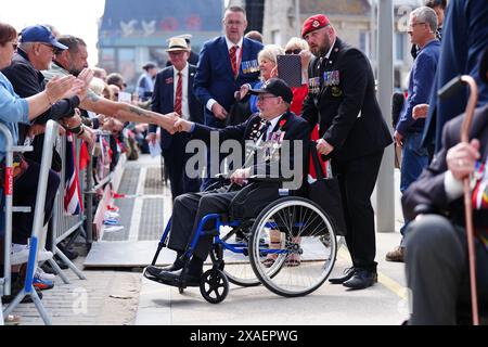 I veterani sono accolti da folle a seguito della sfilata dei veterani con lo Spirit of Normandy Trust, sul lungomare di Arromanches, in Normandia, Francia, per commemorare il 80° anniversario dello sbarco del D-Day. Data foto: Giovedì 6 giugno 2024. Foto Stock