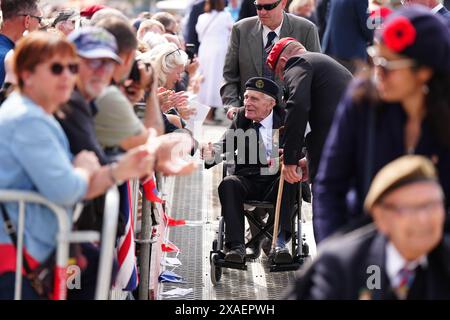 Il veterano John Dennett è accolto da folle a seguito della sfilata dei veterani con lo Spirit of Normandy Trust, sul fronte mare ad Arromanches, in Normandia, Francia, per commemorare il 80° anniversario dello sbarco del D-Day. Data foto: Giovedì 6 giugno 2024. Foto Stock