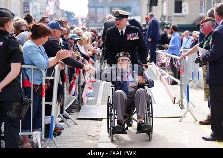 I veterani sono accolti da folle a seguito della sfilata dei veterani con lo Spirit of Normandy Trust, sul lungomare di Arromanches, in Normandia, Francia, per commemorare il 80° anniversario dello sbarco del D-Day. Data foto: Giovedì 6 giugno 2024. Foto Stock