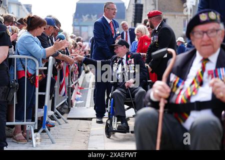 I veterani sono accolti da folle a seguito della sfilata dei veterani con lo Spirit of Normandy Trust, sul lungomare di Arromanches, in Normandia, Francia, per commemorare il 80° anniversario dello sbarco del D-Day. Data foto: Giovedì 6 giugno 2024. Foto Stock