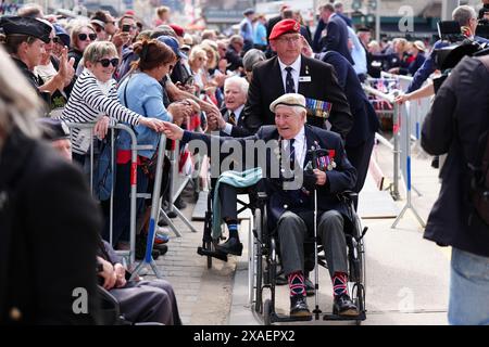 I veterani sono accolti da folle a seguito della sfilata dei veterani con lo Spirit of Normandy Trust, sul lungomare di Arromanches, in Normandia, Francia, per commemorare il 80° anniversario dello sbarco del D-Day. Data foto: Giovedì 6 giugno 2024. Foto Stock