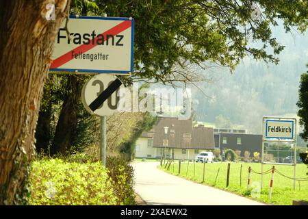 Un cartello con la parola Frastanz è vicino a una strada. La strada è vuota e c'è una casa in lontananza Foto Stock