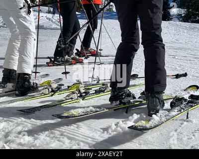 Un gruppo di sciatori si trova su una pista innevata con gli sci. Gli sciatori indossano abiti bianchi e neri Foto Stock