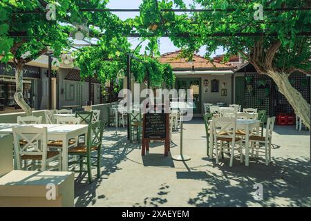 Cefalonia, isola Ionica Grecia, taverna vuota con un'area salotto all'aperto con sedie e tavoli in legno. Foto Stock