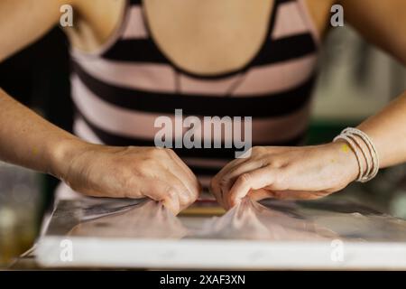 Un'immagine ravvicinata di un'artista femminile che si concentra sulla sua tela, mostrando la sua dedizione e creatività in un ambiente di studio. Foto Stock