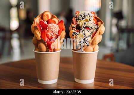 Spalmare i waffle in tazze di gelato con fragole su un tavolo di legno Foto Stock