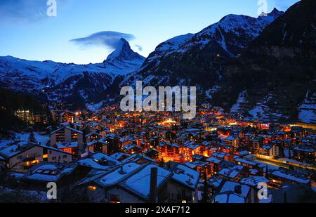 Vista aerea invernale del villaggio di Zermatt di notte, dominato dalla vetta del Cervino nelle Alpi svizzere - paesaggio idilliaco con chalet in legno sur Foto Stock