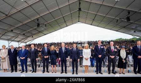 Il presidente francese Emmanuel Macron (C-R) e la moglie del presidente francese Brigitte Macron (5-R) il presidente statunitense Joe Biden (C-L) e la first lady statunitense Jill Biden (6-L) durante la cerimonia commemorativa internazionale tenutasi a Omaha Beach in occasione del 80° anniversario dello sbarco alleato del "D-Day" della seconda guerra mondiale in Normandia, a Saint-Laurent-sur-Mer, nel nord-ovest della Francia, il 6 giugno 2024. Le cerimonie del D-Day del 6 giugno di quest'anno celebrano il 80° anniversario dal lancio dell'operazione Overlord, una vasta operazione militare delle forze alleate in Normandia, che ha cambiato l'onda della seconda guerra mondiale, portando alla fine al Foto Stock