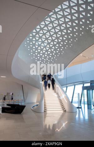 La gente sale le scale nella sala principale. BEEAH Headquarters, Sharjah, Emirati Arabi Uniti. Architetto: Zaha Hadid Architects, 2022. Foto Stock