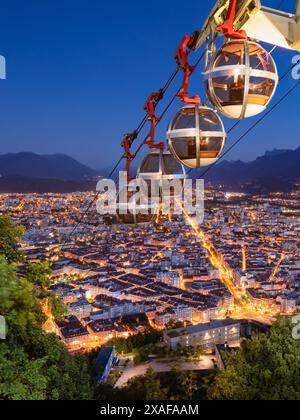 Funivia Grenoble-Bastille (conosciuta come Les Bulles) con vista sopraelevata della città di Grenoble in serata. Isere, Alpi, Francia Foto Stock