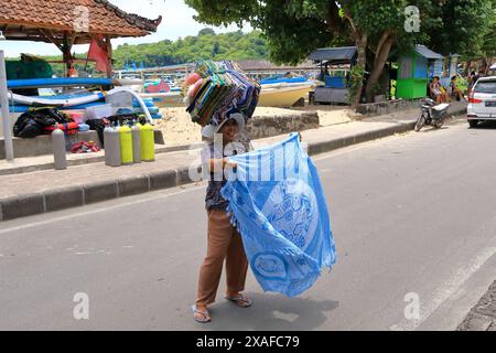 Padang Bai, Bali in Indonesia - 7 febbraio 2024: Donna vende abiti sarong per strada Foto Stock