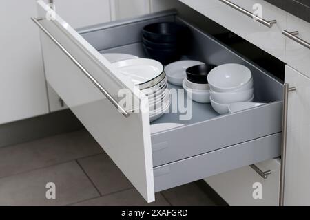 Cassetto aperto della cucina bianco con piatti bianchi e altri piatti all'interno Foto Stock