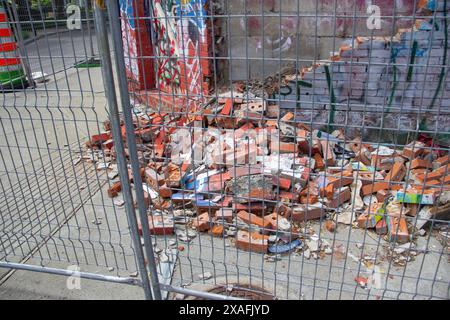 un muro crollato dietro una recinzione Foto Stock