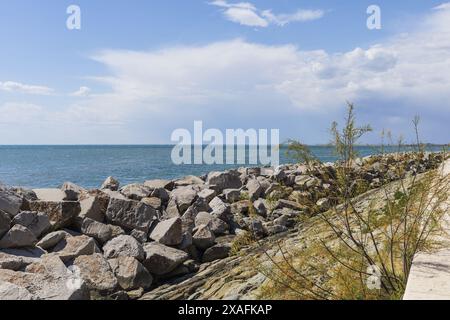 Foto panoramica del mare Adriatico con la costa rocciosa in primo piano con un cielo blu sopra il giorno di sole Foto Stock