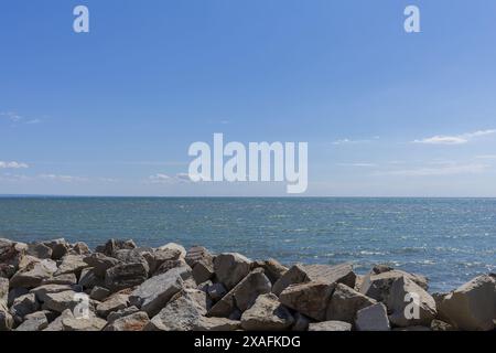 Foto panoramica del mare Adriatico con la costa rocciosa in primo piano con un cielo blu sopra il giorno di sole Foto Stock