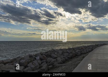 Foto panoramica del mare Adriatico con spiaggia rocciosa in primo piano al tramonto Foto Stock