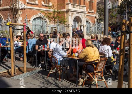 Valencia, Spagna - 24 marzo 2024: Le persone mangiano al ristorante seduti fuori ai tavoli Foto Stock