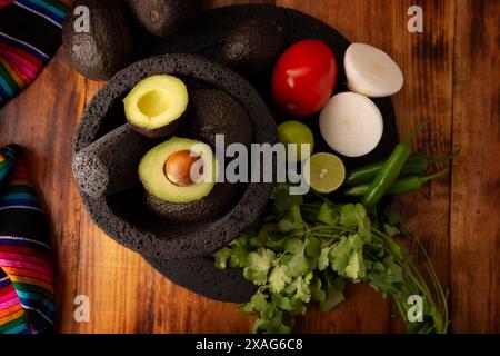 Ingredienti di base per preparare la salsa di avocado conosciuta come guacamole, realizzata in una molcajete di pietra vulcanica, una salsa molto popolare a base di avocado. Ricetta tradizionale Foto Stock