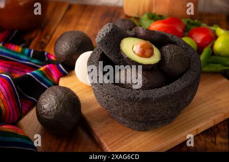 Ingredienti di base per preparare la salsa di avocado conosciuta come guacamole, realizzata in una molcajete di pietra vulcanica, una salsa molto popolare a base di avocado. Ricetta tradizionale Foto Stock