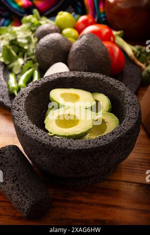 Ingredienti di base per preparare la salsa di avocado conosciuta come guacamole, realizzata in una molcajete di pietra vulcanica, una salsa molto popolare a base di avocado. Ricetta tradizionale Foto Stock