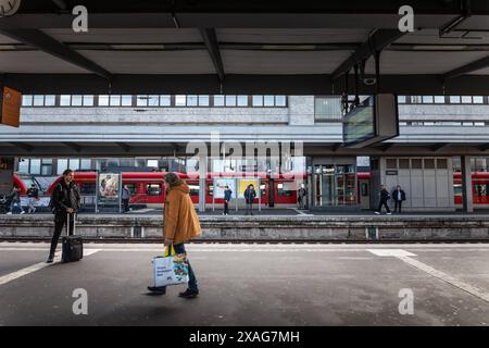 Un'istantanea della vita quotidiana alla stazione ferroviaria di Essen Hauptbahnhof in Germania, dove la gente aspetta i treni sulle banchine. Questa foto cattura l'essenc Foto Stock