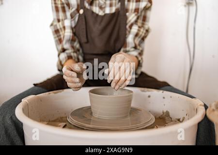 La giovane donna che scolpisce la ciotola di ceramica utilizzando la ruota di potter. Mani che modellano l'argilla in piatto in uno studio di artigianato. Foto Stock