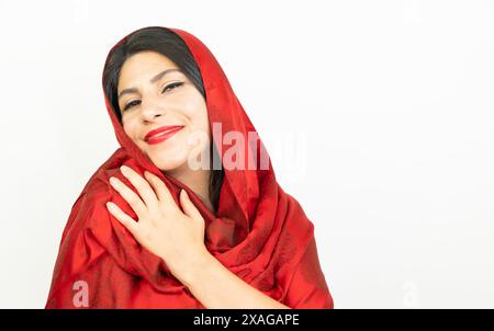 Ritratto di una donna con una sciarpa rossa in studio. giovane donna mediorientale, sfondo bianco Foto Stock