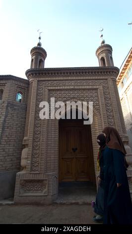 Donne Uyghur che vendono cose sotto una piccola moschea nella città vecchia di Kashgar, Xinjiang, Cina. Foto Stock