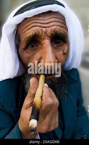 Un uomo palestinese anziano che fuma la sigaretta nel quartiere musulmano della città vecchia di Gerusalemme. Foto Stock