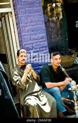 Uomini egiziani che fumano Shisha. (Tubo dell'acqua) in un piccolo caffè al Cairo, in Egitto. Foto Stock