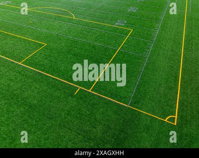 Foto aerea nel tardo pomeriggio della linea di calcio grigia con linee di calcio gialle su un campo artificiale in erba sintetica. Foto Stock