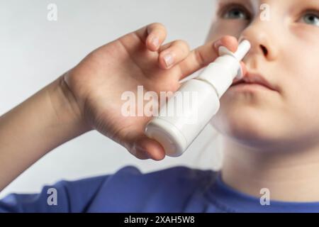 Una ragazza spruzza uno spray contro il naso che cola e la congestione nasale nei suoi seni. Trattamento di sinusite e sinusite, spray antimicrobico. Foto Stock