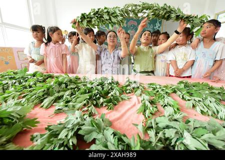 I bambini imparano le usanze popolari del Dragon Boat Festival nella città di Lianyungang, nella provincia cinese di Jiangsu, 4 giugno 2024. Foto Stock