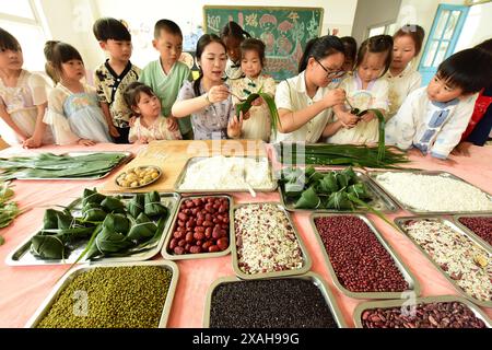 I bambini imparano le usanze popolari del Dragon Boat Festival nella città di Lianyungang, nella provincia cinese di Jiangsu, 4 giugno 2024. Foto Stock