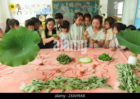 I bambini imparano le usanze popolari del Dragon Boat Festival nella città di Lianyungang, nella provincia cinese di Jiangsu, 4 giugno 2024. Foto Stock