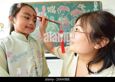 I bambini imparano le usanze popolari del Dragon Boat Festival nella città di Lianyungang, nella provincia cinese di Jiangsu, 4 giugno 2024. Foto Stock