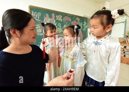 I bambini imparano le usanze popolari del Dragon Boat Festival nella città di Lianyungang, nella provincia cinese di Jiangsu, 4 giugno 2024. Foto Stock