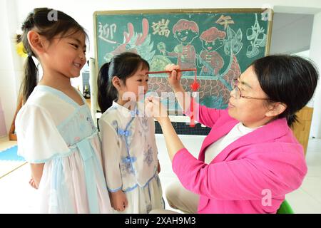 I bambini imparano le usanze popolari del Dragon Boat Festival nella città di Lianyungang, nella provincia cinese di Jiangsu, 4 giugno 2024. Foto Stock