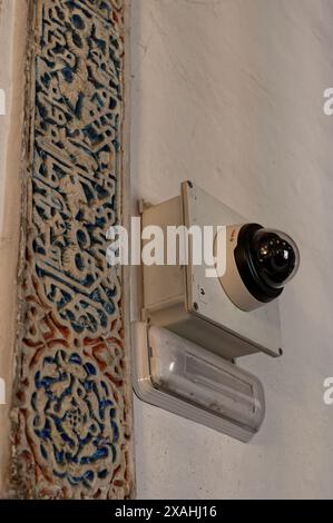 Telecamera di sicurezza montata su una parete con intricate incisioni nell'alcazar reale di siviglia, che fonde la sorveglianza moderna con l'arte storica Foto Stock