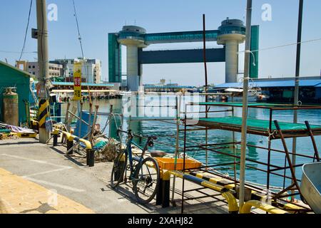 Samcheok City, Corea del Sud - 18 maggio 2024: Una bicicletta parcheggiata in primo piano con la Torre di sicurezza dello Tsunami visibile all'ingresso del porto di Samcheok, Foto Stock
