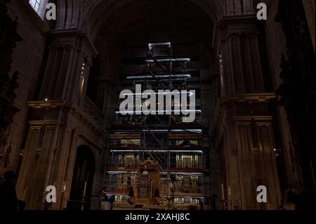Un'impalcatura illuminata circonda l'intricato altare di una cattedrale storica mentre sono in corso lavori di restauro Foto Stock