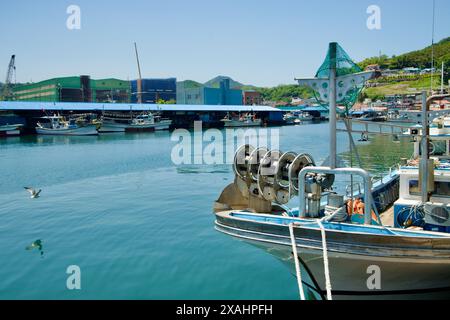 Samcheok City, Corea del Sud - 18 maggio 2024: Barche da pesca attraccate al porto di Samcheok con edifici industriali sullo sfondo, che mostrano il du del porto Foto Stock