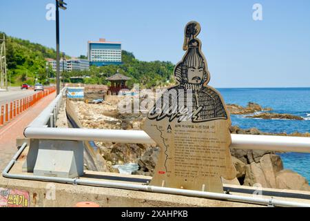 Samcheok City, Corea del Sud - 18 maggio 2024: Un cartello raffigurante il generale Isabu si erge lungo la costa di Samcheok vicino a una costa rocciosa e al tradizionale pav Foto Stock