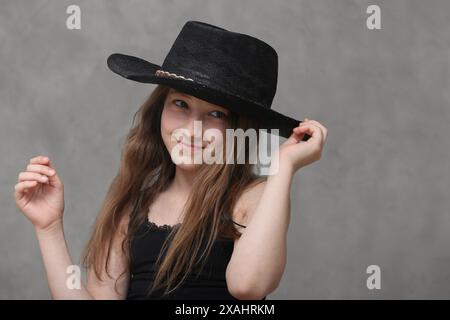 carina e allegra ragazza preadolescente con capelli lunghi che indossa un cappello Foto Stock