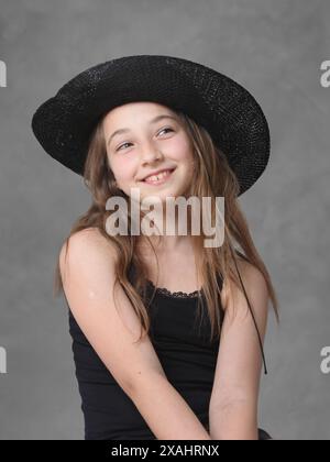 carina e allegra ragazza preadolescente con capelli lunghi che indossa un cappello Foto Stock