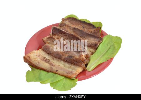 Nell'immagine, pezzi spessi di pancetta vengono fritti su foglie verdi. Foto Stock