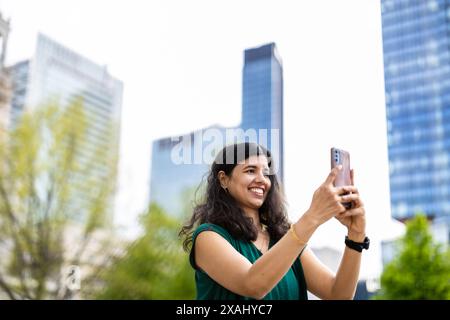 Sorridente giovane donna che usa il suo smartphone in città Foto Stock