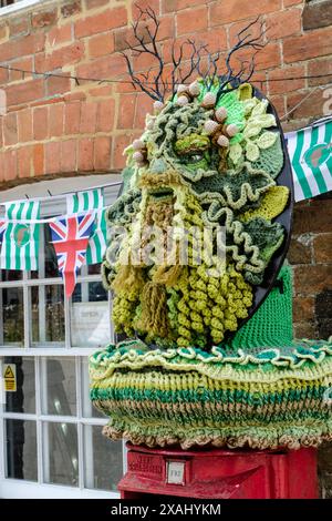 Avebury, Regno Unito. 7 giugno 2024. Ad Avebury è arrivato un topper a maglia di Green Man. Il villaggio, famoso per essere collocato all'interno di un cerchio di pietre preistoriche, attrae molte persone interessate a stili di vita naturali e turisti convenzionali. Si ritiene che l'uomo Verde rappresenti il ciclo della vita, della morte e della rinascita. Crediti: JMF News/Alamy Live News Foto Stock