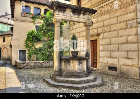 Un antico e bellissimo pozzo d'acqua nella città di San Giulio sul Lago d'Orta in una giornata di sole in Piemonte, Italia Foto Stock